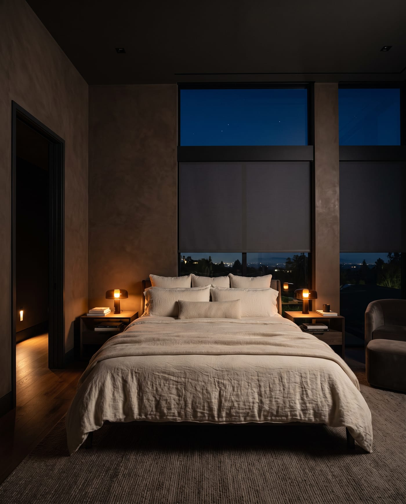 A bedroom at night, shades lowered, two low amber lamps and a faint path light